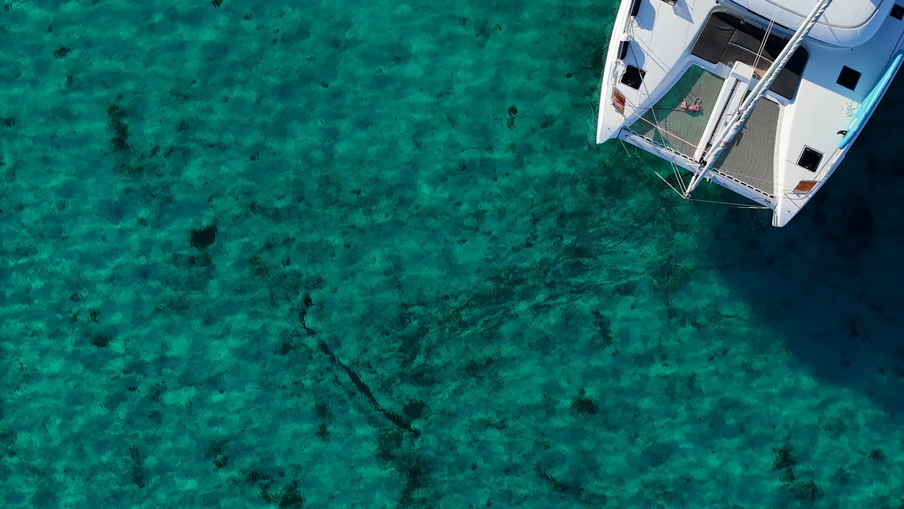 Aerial view of a catamaran bow above clear turquoise water