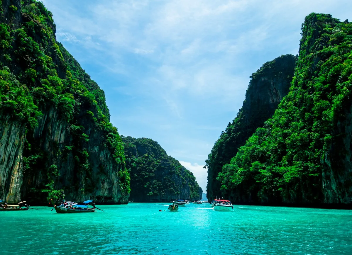 Boats beneath limestone cliffs at Pileh Cove in Thailand